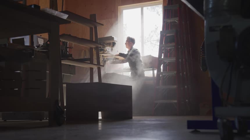 A man works with a piece of wood in a workshop