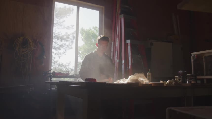 A man sits at a desk next to a casement window writing