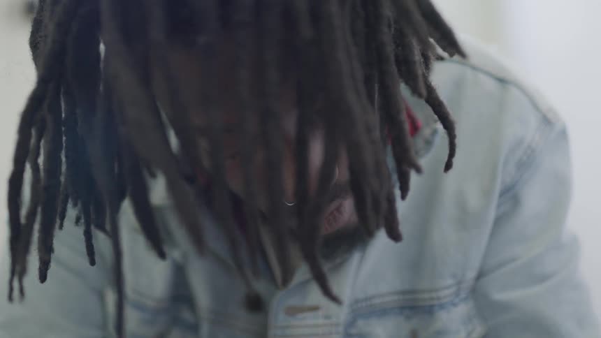 Male with dreads looking down
