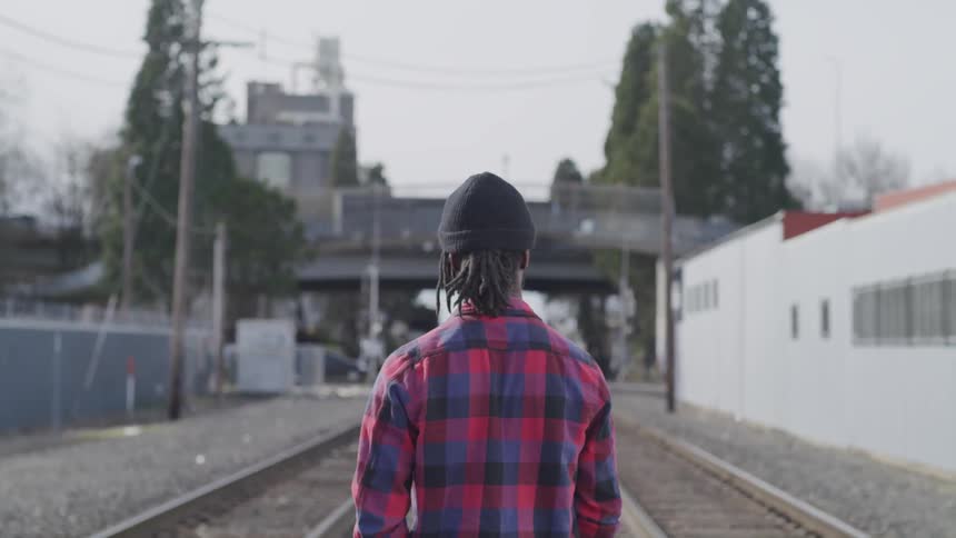 A man stands in between two train tracks and watches traffic pass by