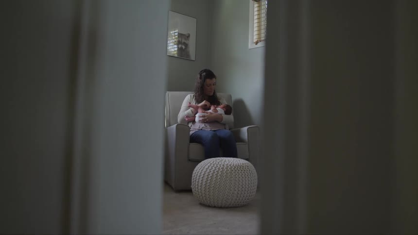 A woman sitting in a chair holds a baby in her arms