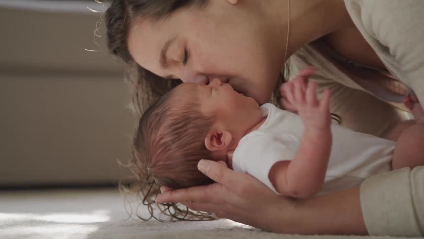 A woman holding and kissing a baby