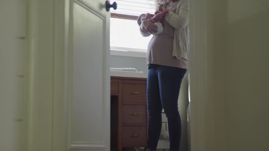 Woman holds and gently sways with newborn baby