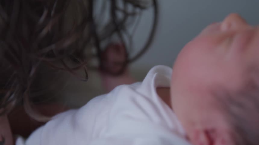 A baby is sleep on the hand of his mother