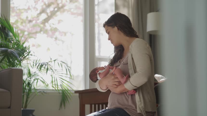 Woman holds baby indoors during daylight