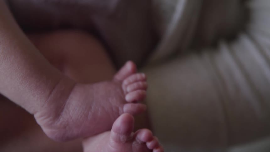 A newborn moves its bare feet