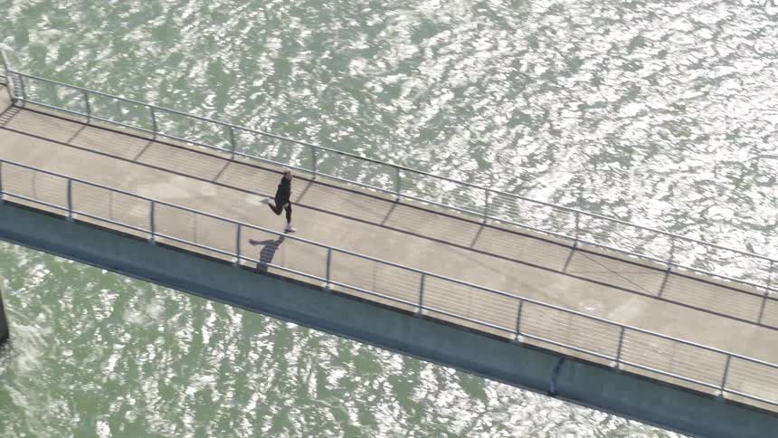 A man runs across a bridge over the water