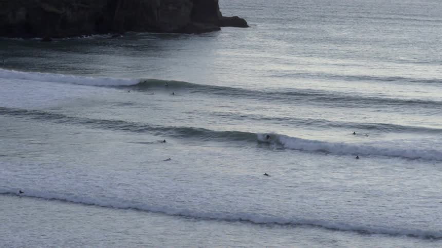 People are surfing in a body of water on a cloudy day