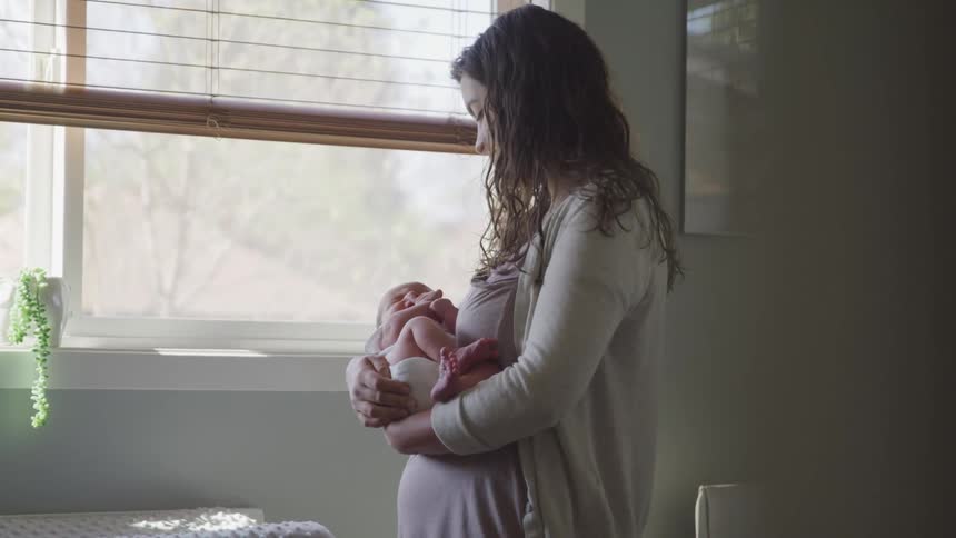 Mother carefully carry her baby and take him to nap