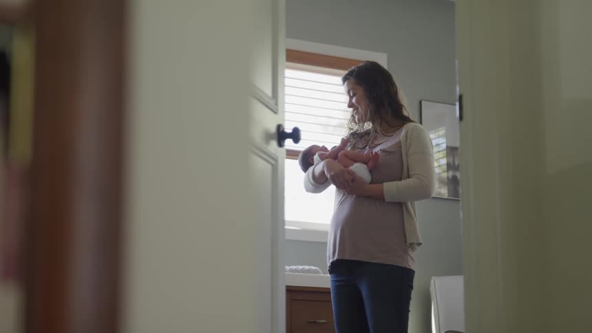 A woman rocks a newborn baby in her arms