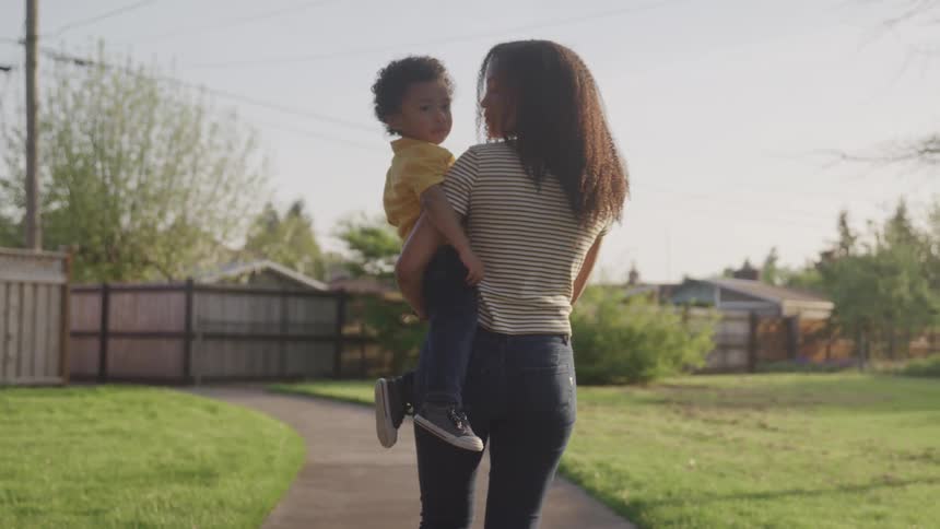 A young black woman carrying a child down a path