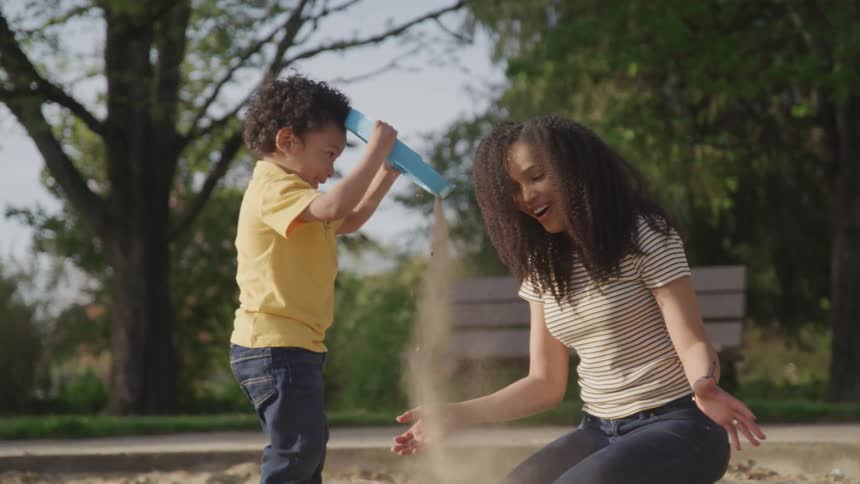 Mother play with her son in the sandbox at the park