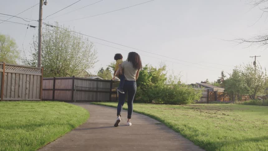 A woman walking on a pathway holding a child