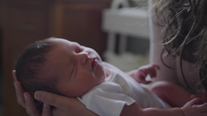 Woman holds baby indoors during daylight