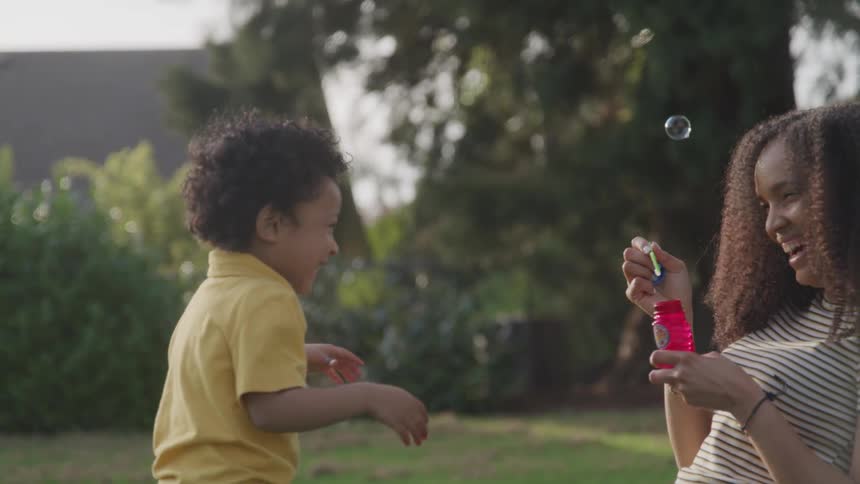Mother and son playing with bubbles at the garden
