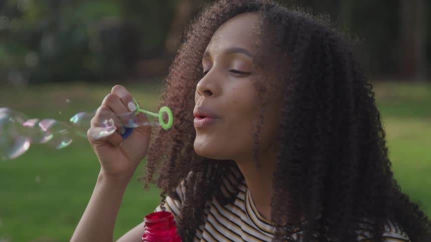 A woman blows bubbles from a small bottle