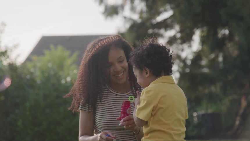 Mother and son play with soap bubbles outside