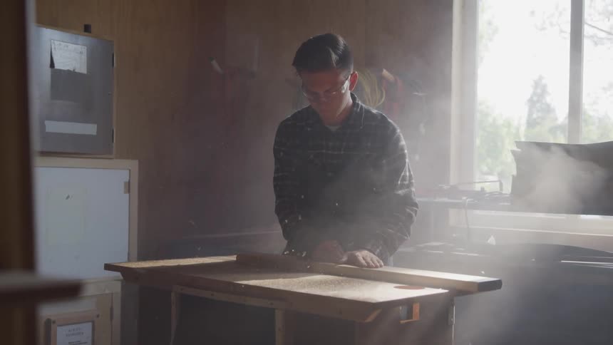 A man cutting a board with a table saw