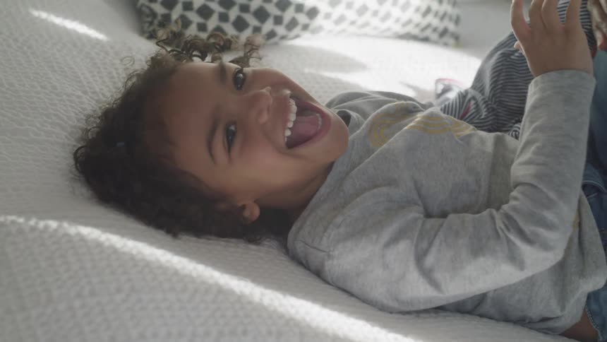 A person tickles a child laying on a bed
