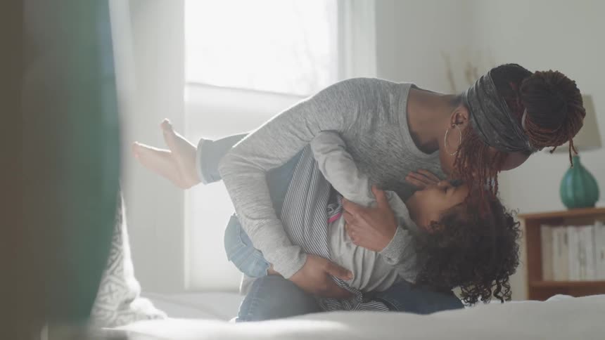 A woman holds a child in her arms and kisses her
