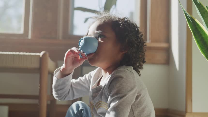 Little boy playing pretend drinking tea from a toy tea cup