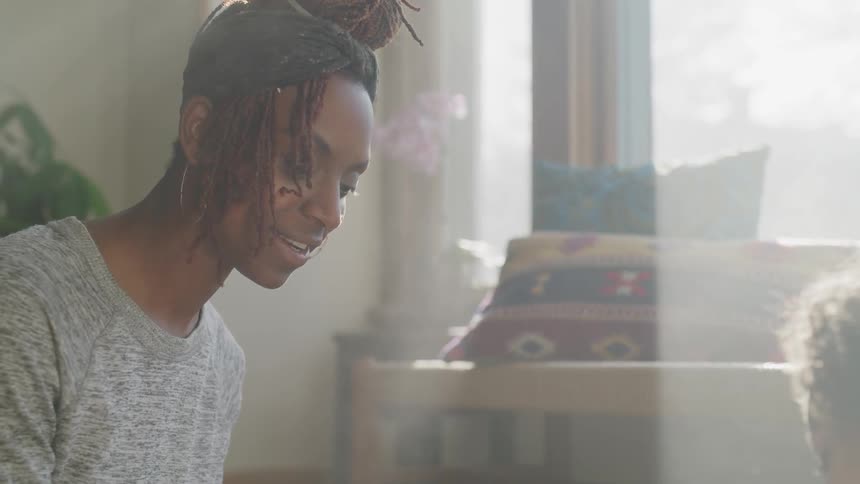 A black woman sitting on the floor speaking with a child