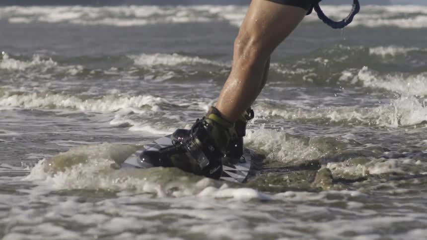 A man skims across ocean waves on a kiteboard, propelled by wind and movement.
