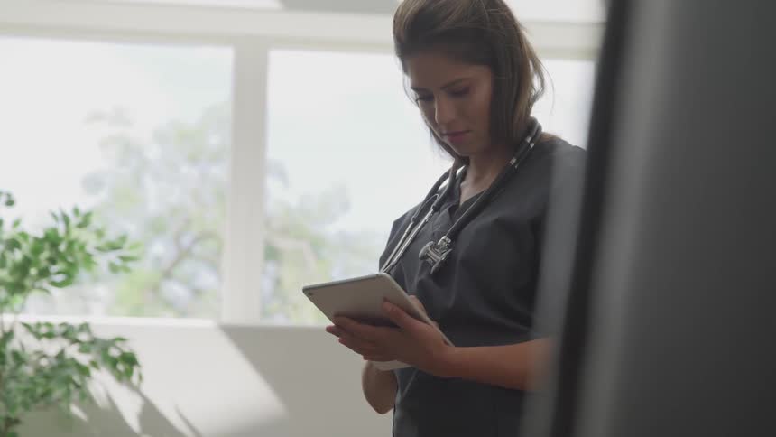 Woman doctor uses tablet in the office during daylight