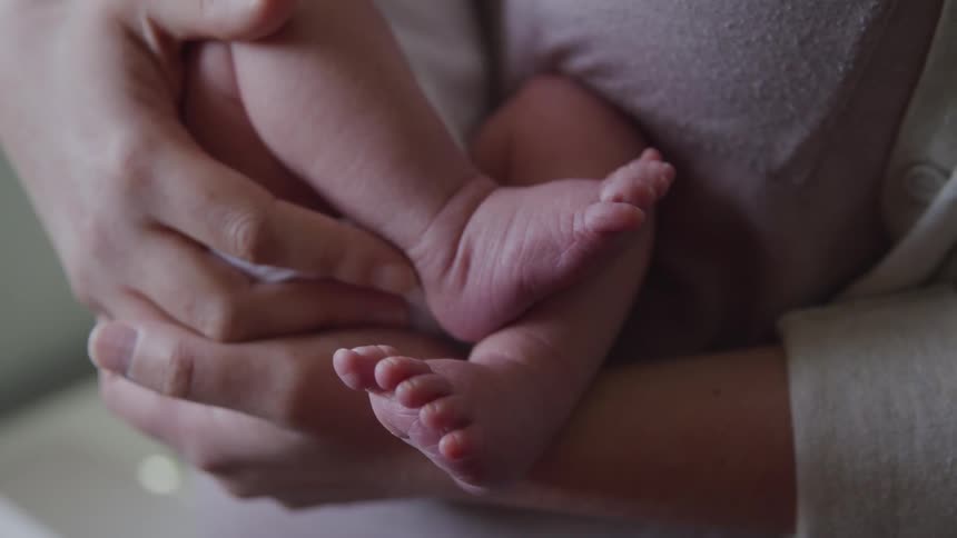 A person holds a newborn tight in their arms