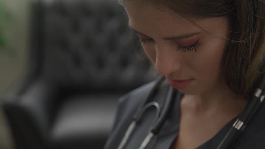 Woman in scrubs looks down