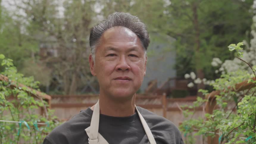 An asian man stands outside and looks around