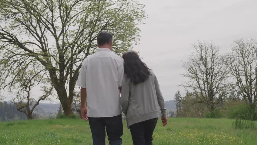 A man and a woman walking on grass holding hands