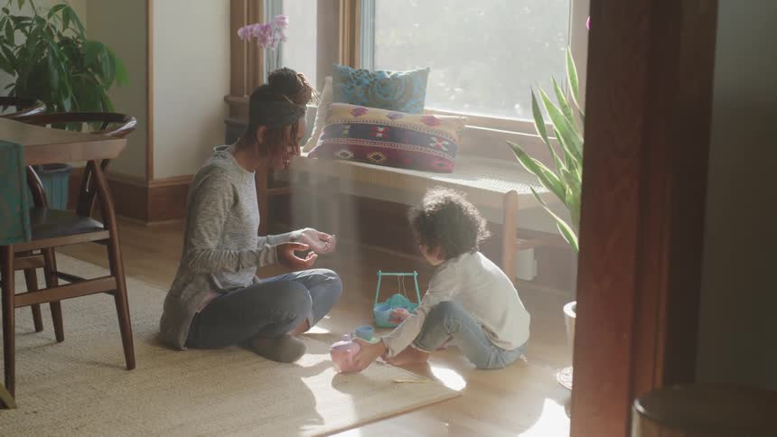 A mother and child have a tea party near the window