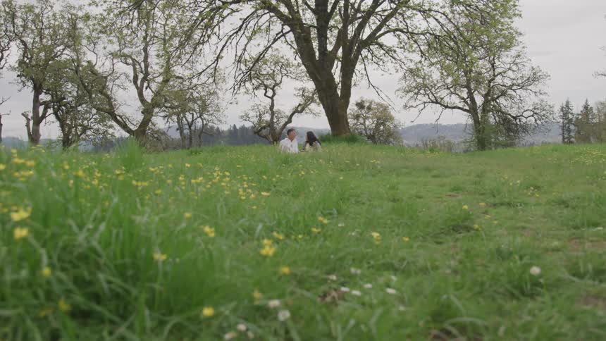 A man and a woman sit in a grassy field