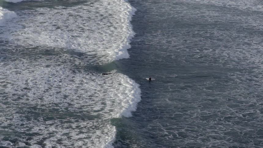 Large waves are heading towards people in a large body of water