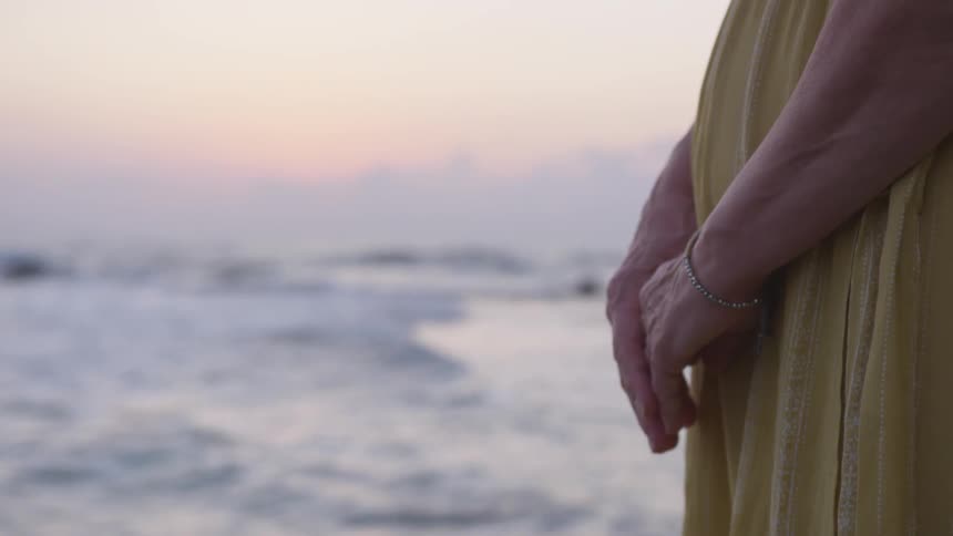 An old woman hold her hand near the beach