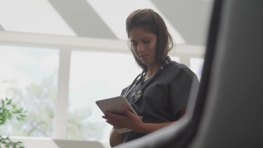 A female nurse looks at a tablet