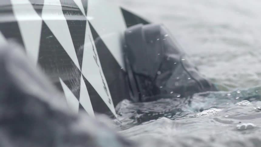 Water slowly crashes against a surfboard on a cloudy day