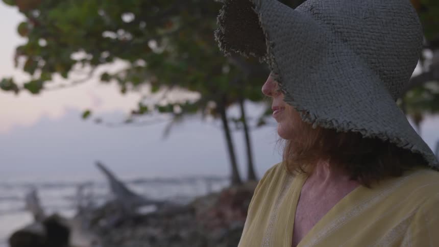 Woman wearing a sun hat looks out at the water