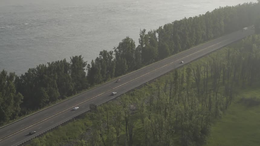 A car drives down the highway by the water