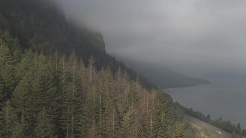 Cars are driving on a road along the wooded mountains