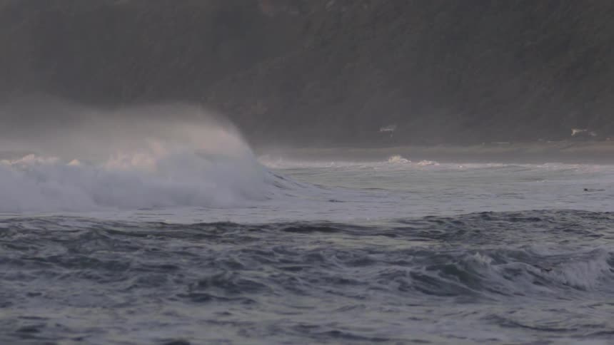 Waves crash along the shore on a cloudy day