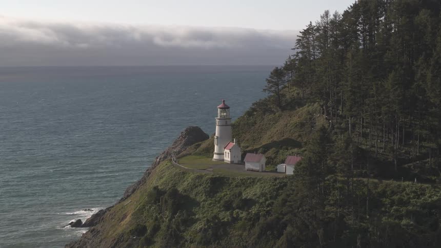 Three houses and a lighthouse on a cliff overlooking the ocean