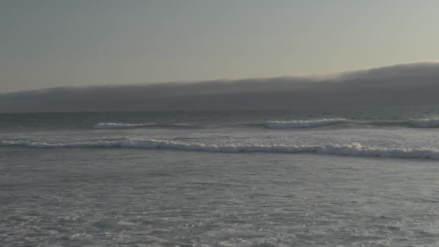 A beach with waves and the sky in the background