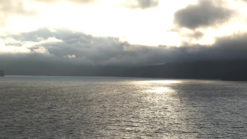 Clouds and land on the horizon with sunlight shimmering on the ocean surface