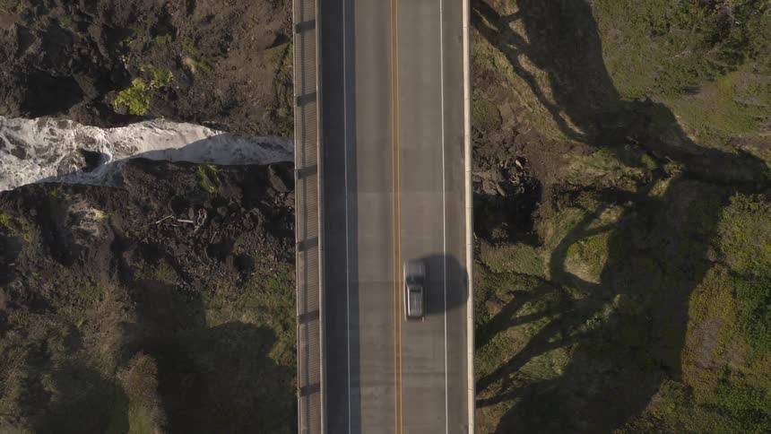 Bird eye view of a bridge with a vehicle passing it