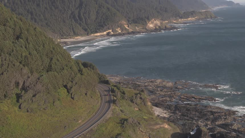 A car drives along a highway next to the coast