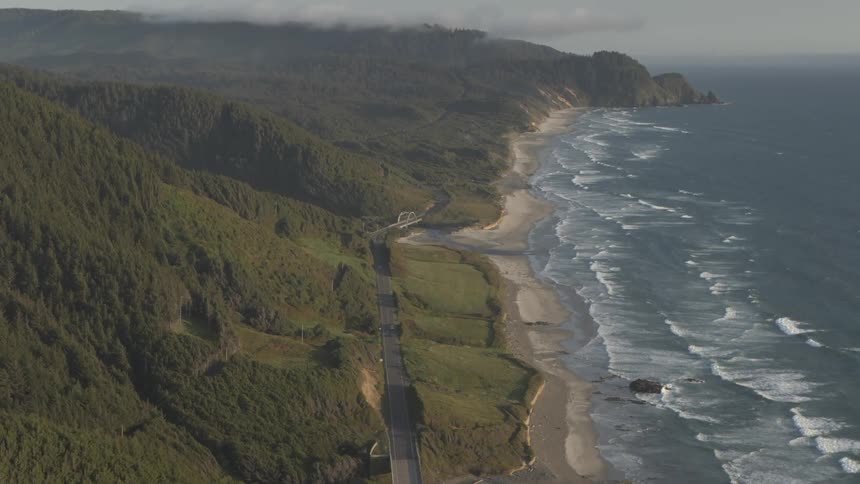 A car travels down a road that runs along a coastline