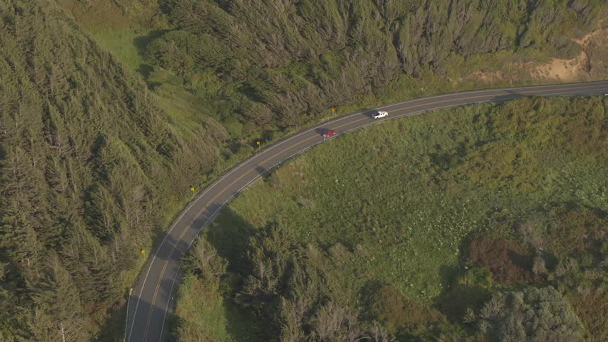 Cars driving on a road near a hillside