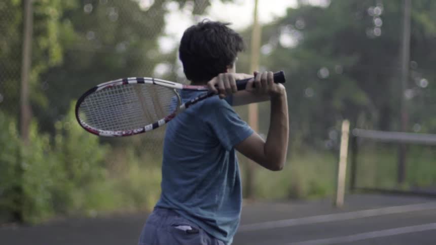 A man hitting a tennis ball with a racket on a sunny day